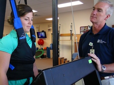 Patient using treadmill under supervision of therapist